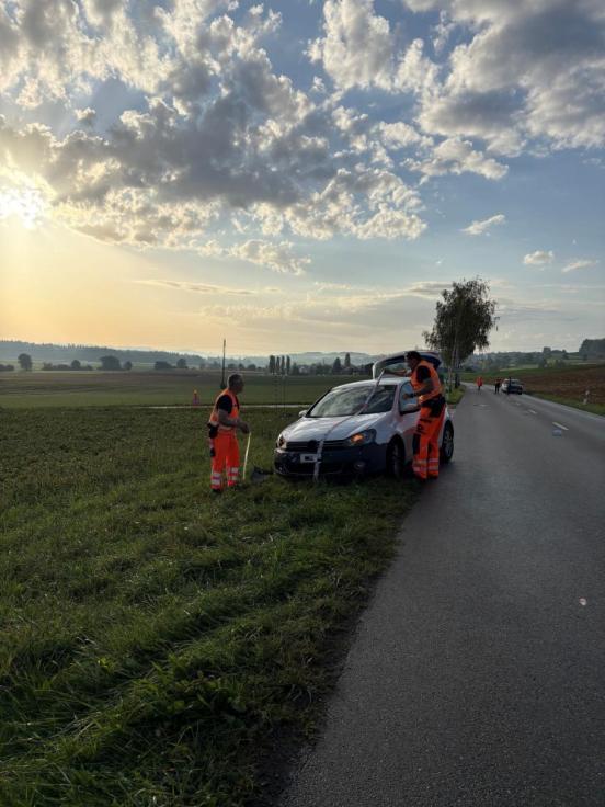 Zwei Polizisten nehmen Spuren an einem Unfallfahrzeug.