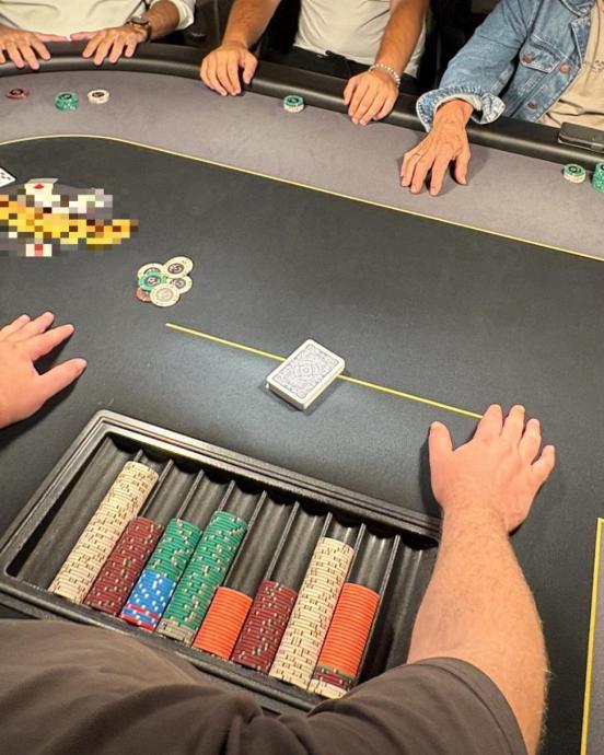Ein Pokertisch, an welchem diverse Personen zu sehen sind.