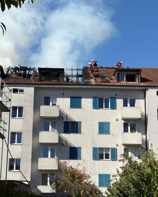 Feuerwehrleute auf dem Dach eines brennenden Mehrfamilienhauses