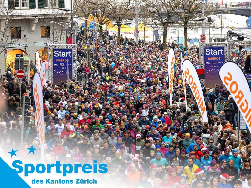 Eine Masse an Läuferinnen und Läufern rennen auf der Strecke des Zürcher Silvesterlaufs am Limmatquai der Stadt Zürich entlang.