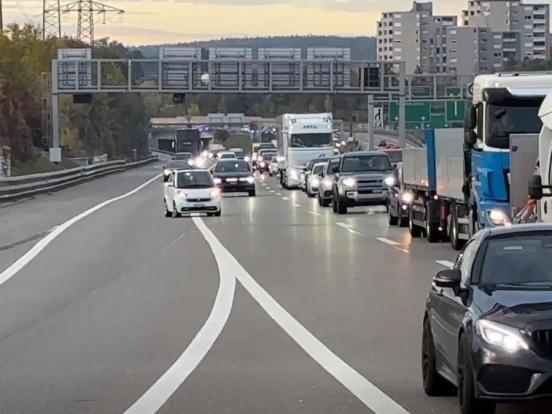ein weisses Fahrzeug überfährt auf der Autobahn mit stockendem Verkehr eine Sicherheitslinie