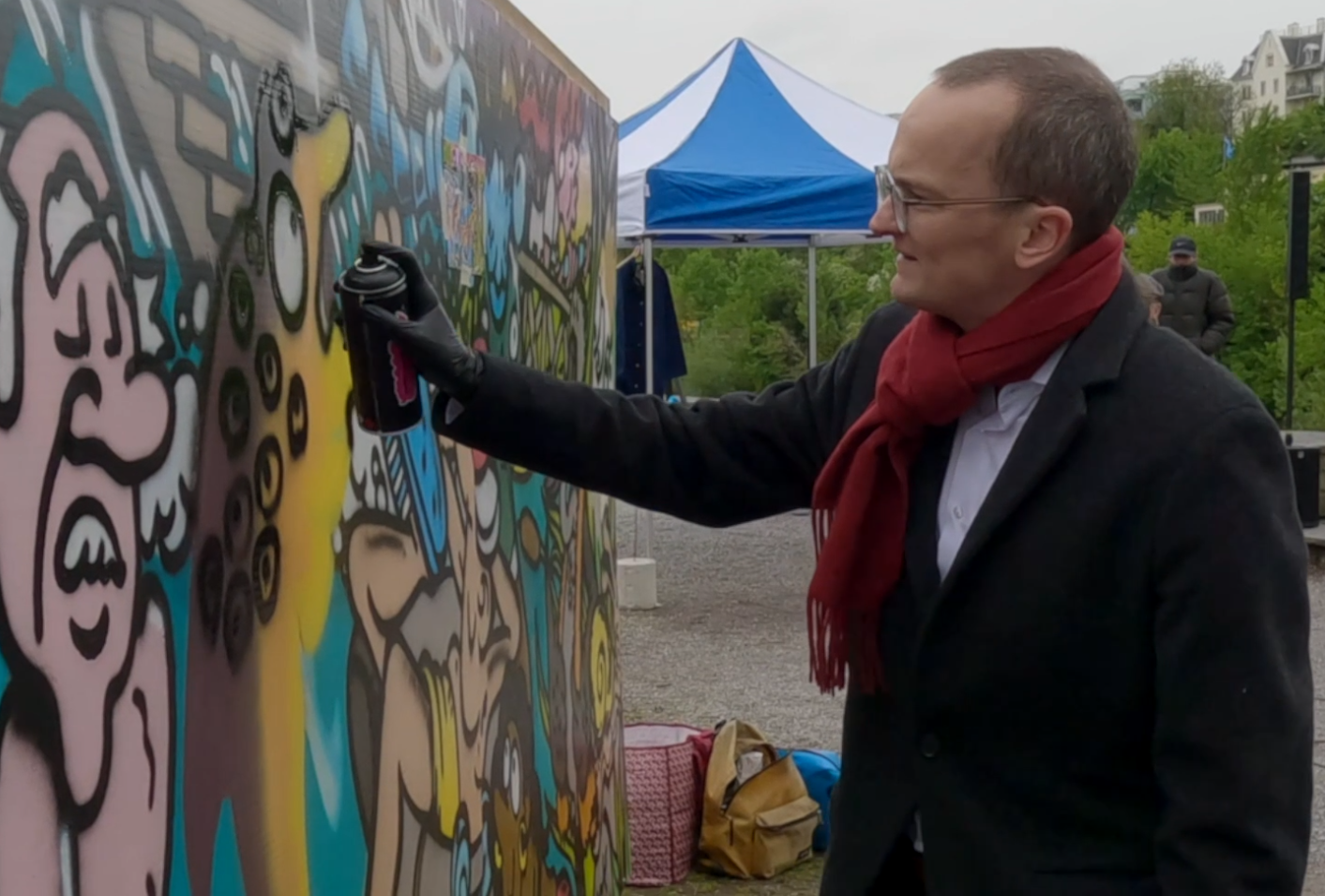 Martin Neukom steht vor einer Graffiti-Wand und vollendet mit einer Sprühdose das Graffiti.