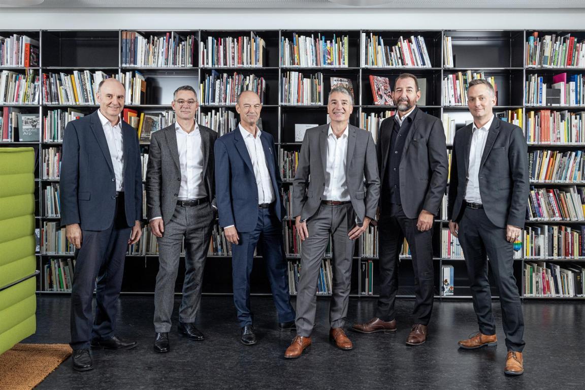 Auf dem Bild sieht man die sechs Mitglieder der Geschäftsleitung, stehend in der Cafeteria des Hochbauamtes. Von links nach rechts ist zu sehen: Beat Wüthrich, Adriano Tettamanti, Daniel Baumann, Beat Pahud (Kantonsbaumeister), David Vogt, Claus Frei.