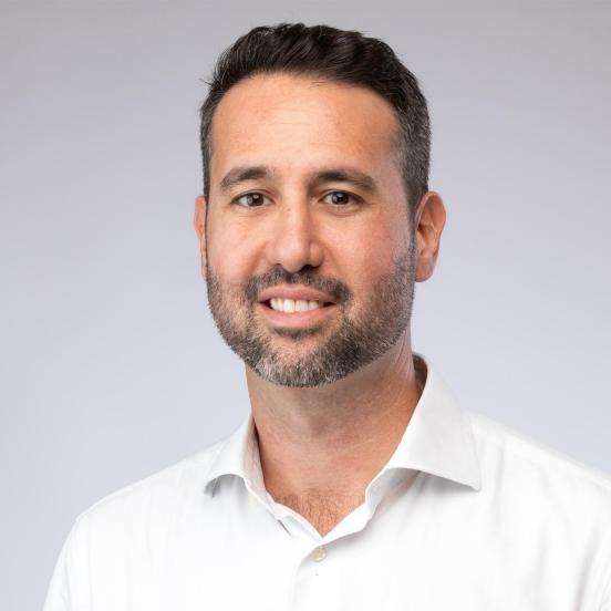 nicola lächelt in die kamera. er hat ein weisses Hemd an.