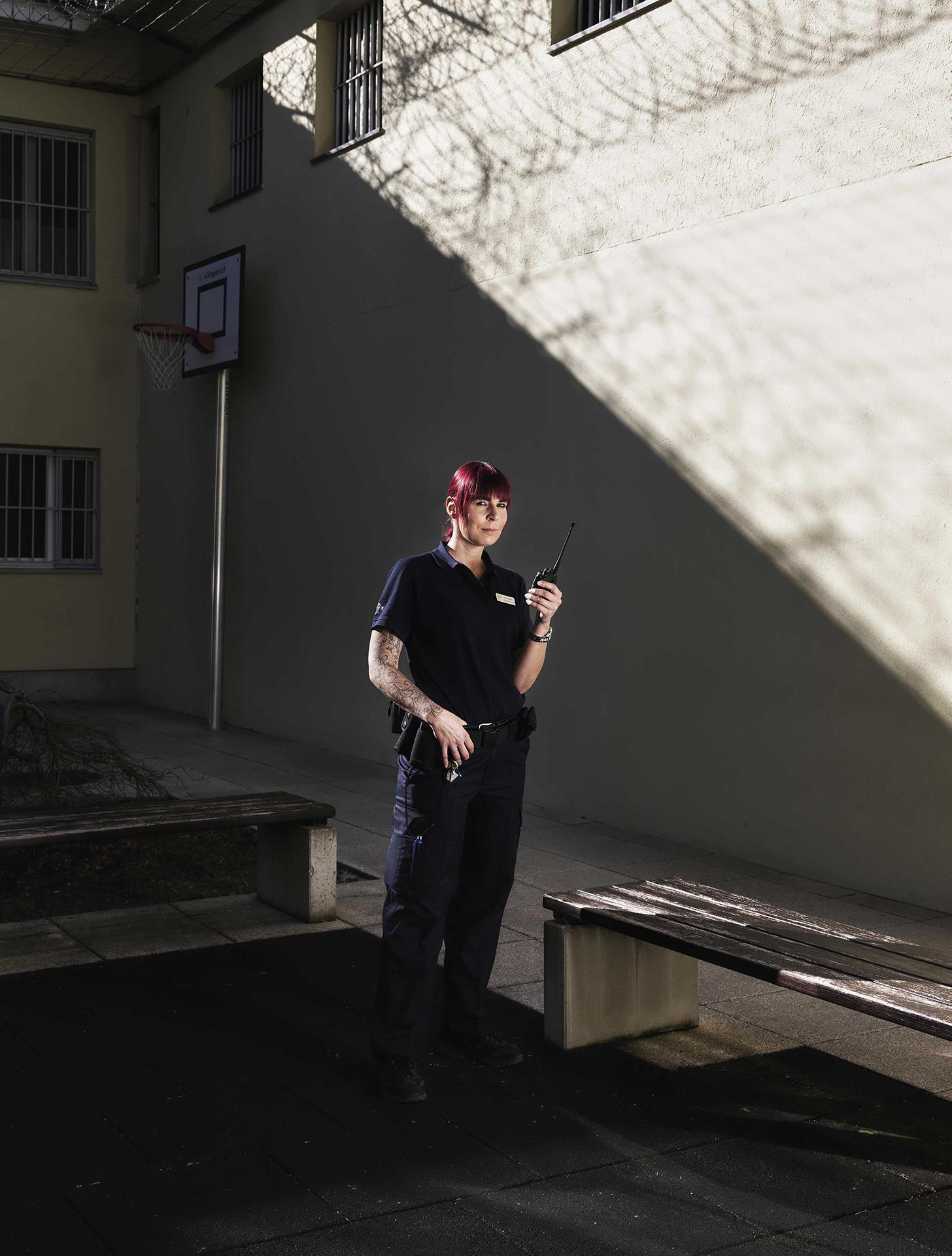 Fachfrau Justizvollzug steht im Gefängnishof und spricht ins Funkgerät