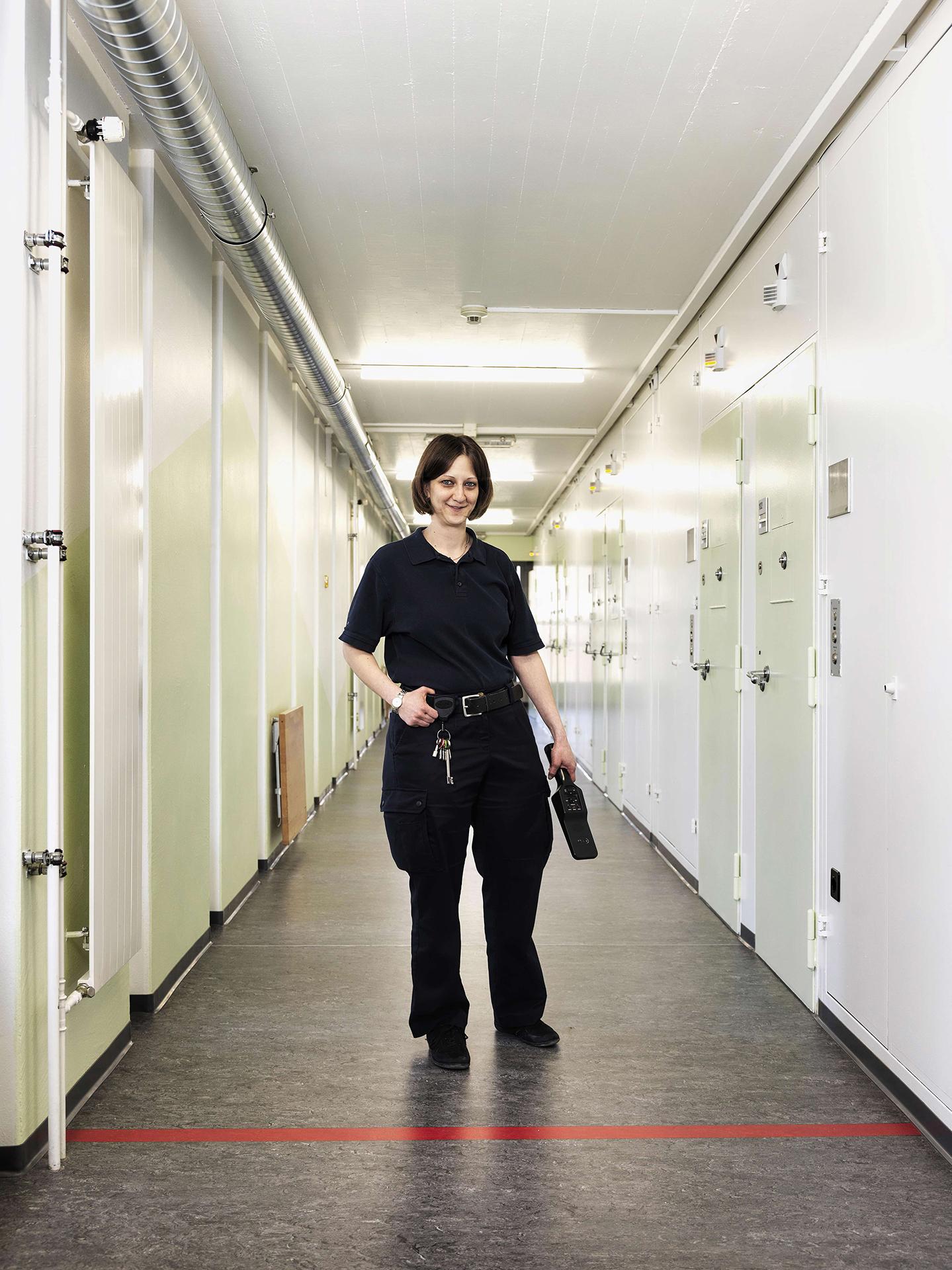 Fachfrau Justizvollzug in Uniform geht durch den Gefängniskorridor