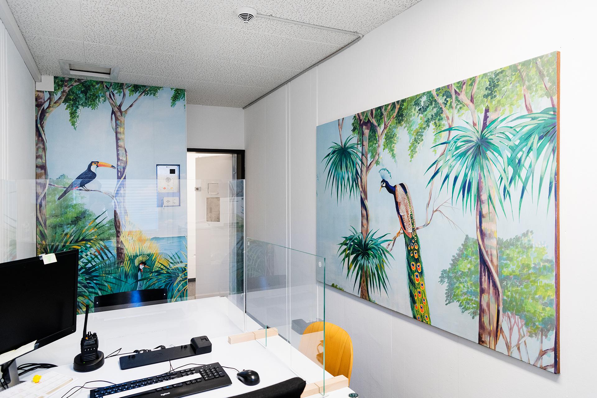 Büro mit bunter Wandbemalung, Tisch mit Computer und Stühlen