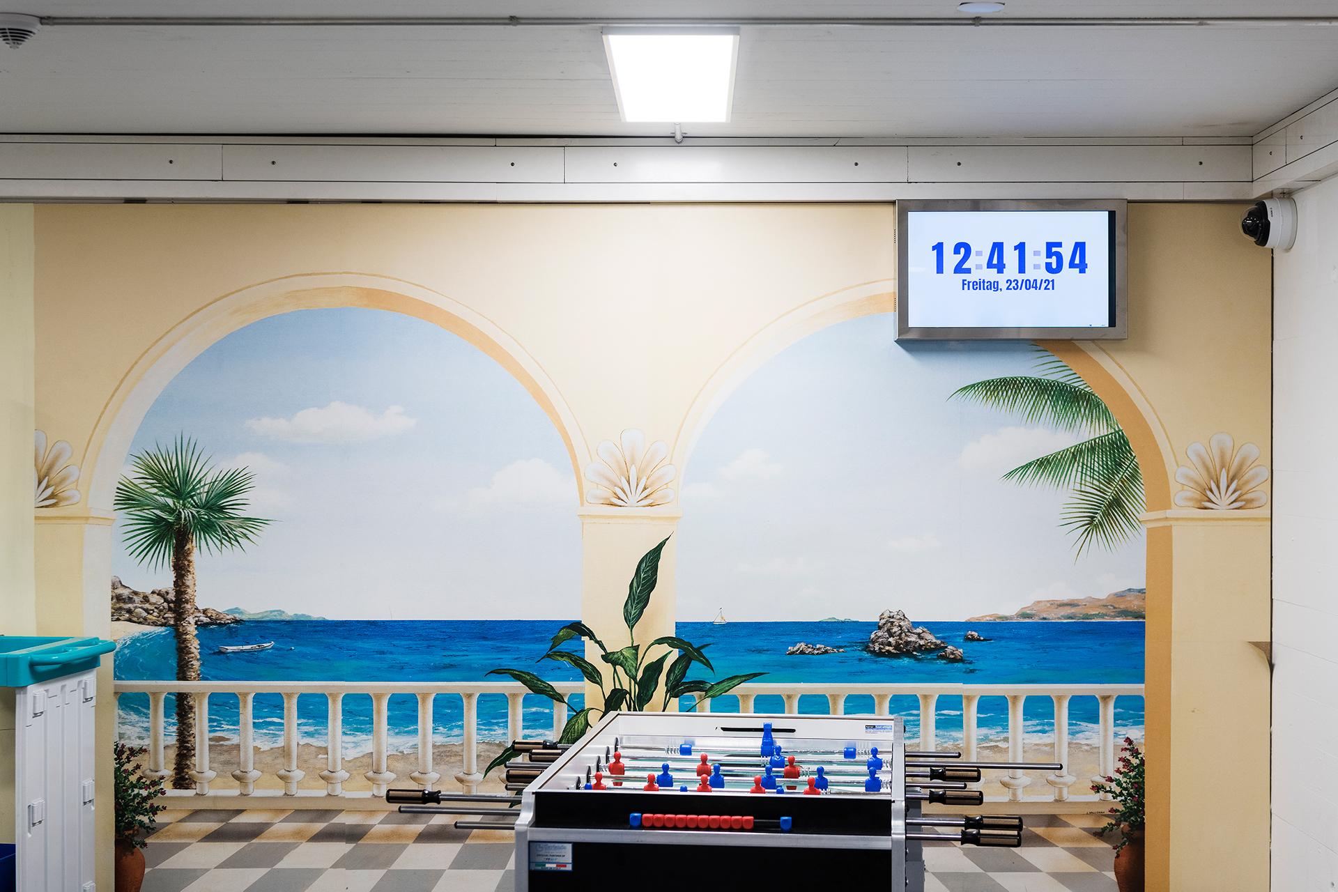 Töggelikasten vor einer Wand die bemalt ist mit Sicht aufs Meer