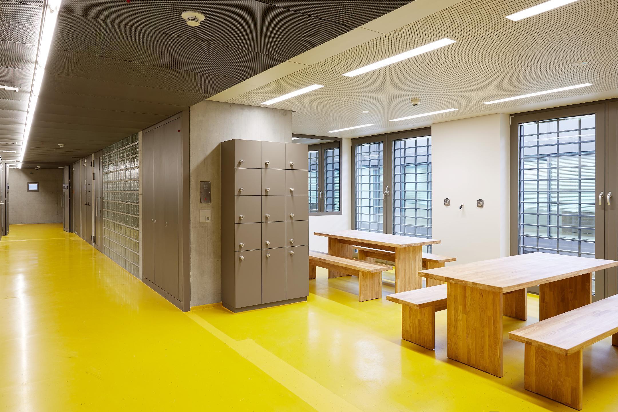 hell beleuchteter Korridor mit Schrank und Tischen vor vergitterten Fenstern