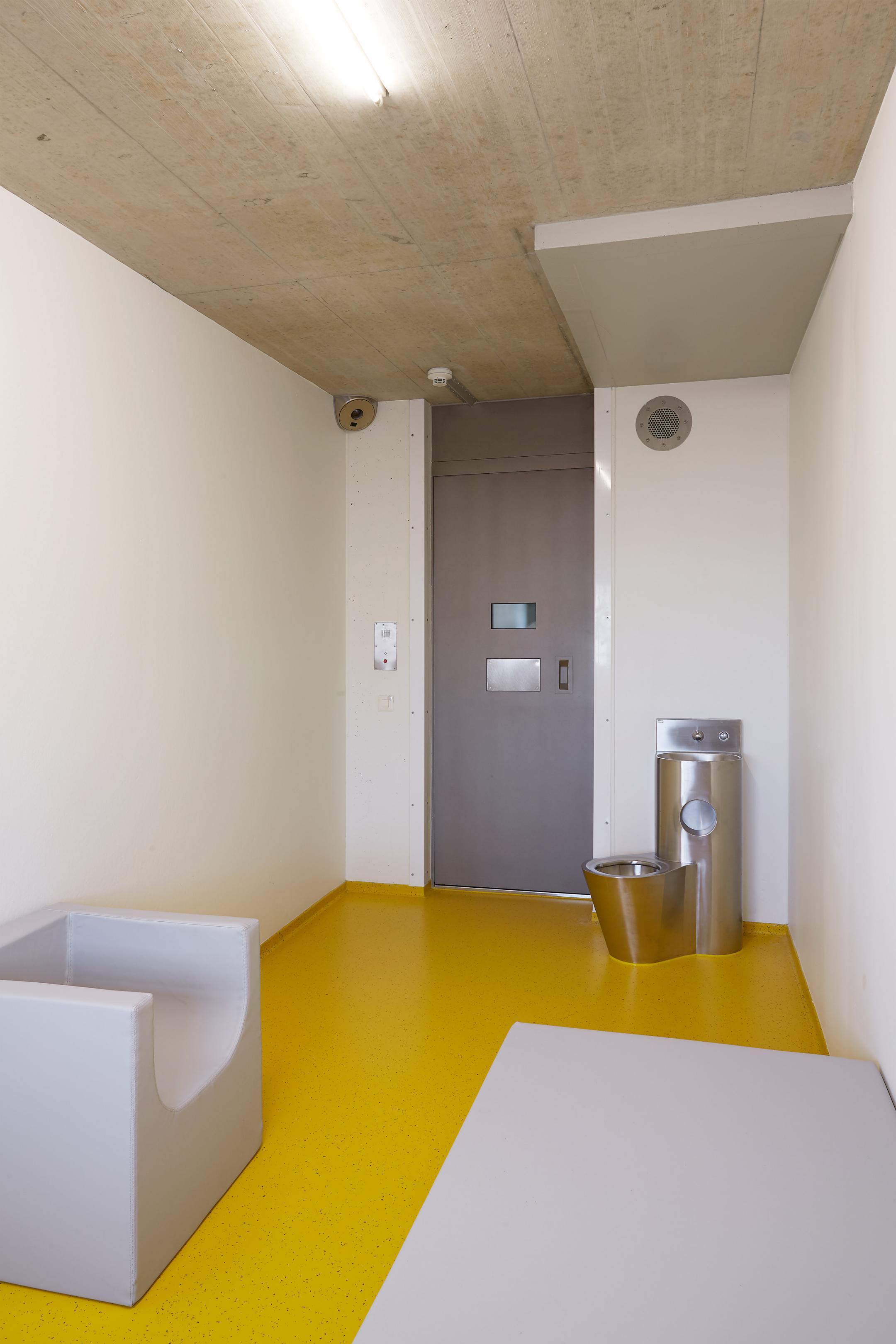 Kleiner, kahler Raum mit Toilette und Sitzgelegenheit