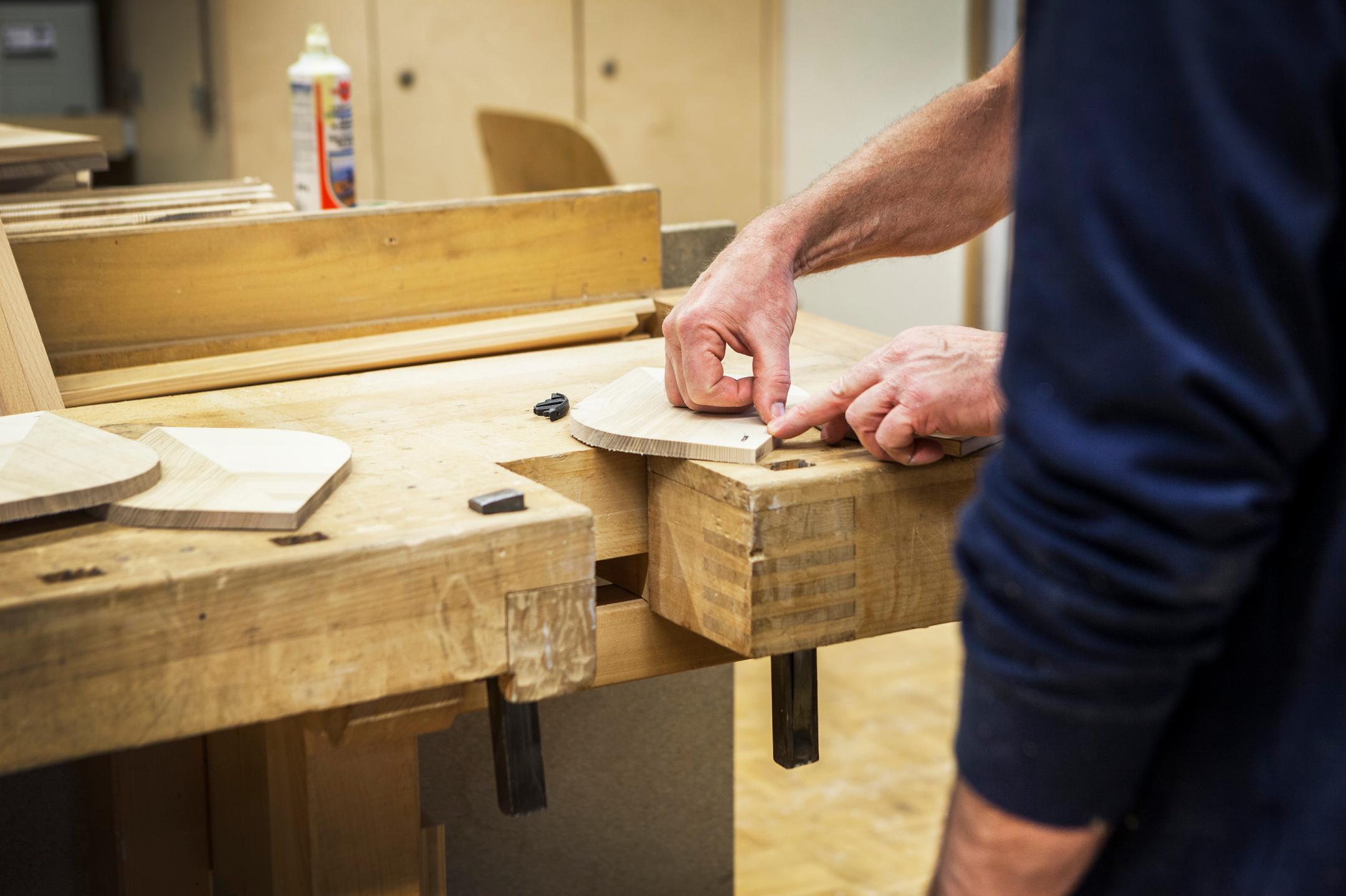 Zwei Personen an einer Werkbank mit Holz und Leim.