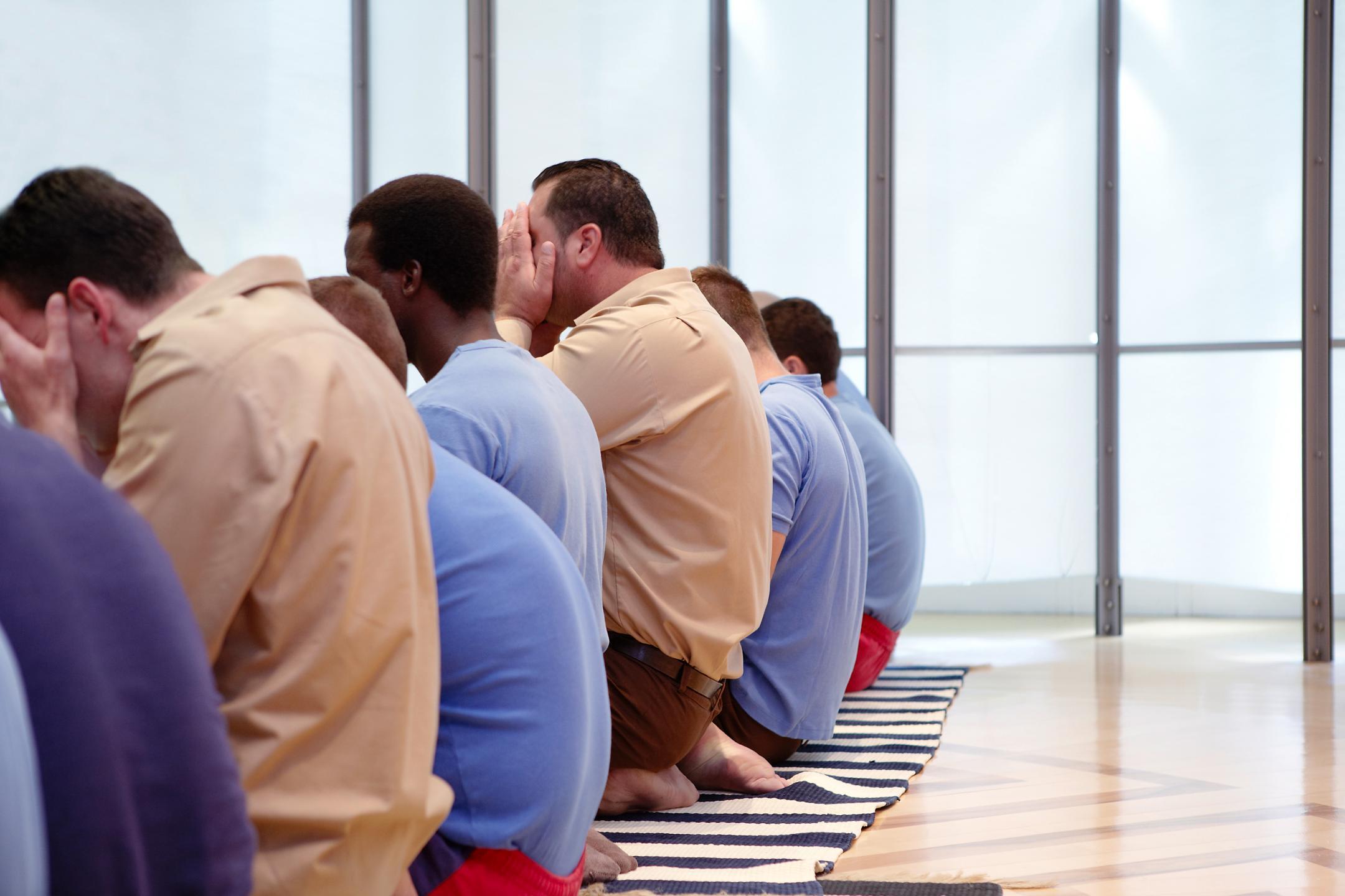 Männer auf Gebetsteppichen beim Gebet.