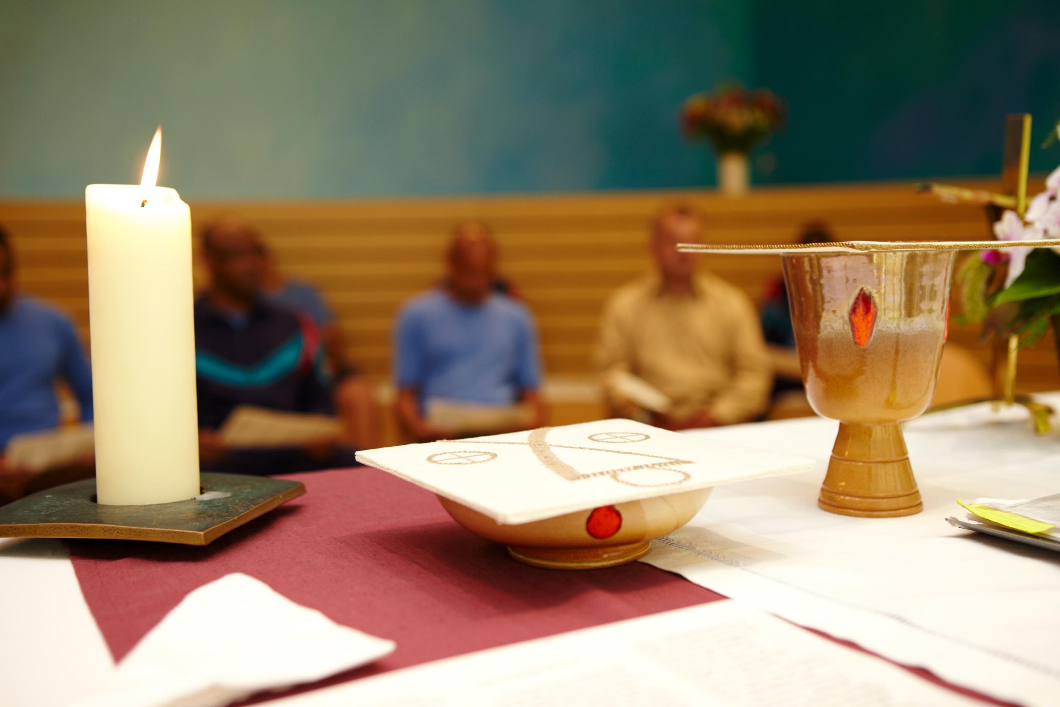 Kerze und Hostien auf Altar.