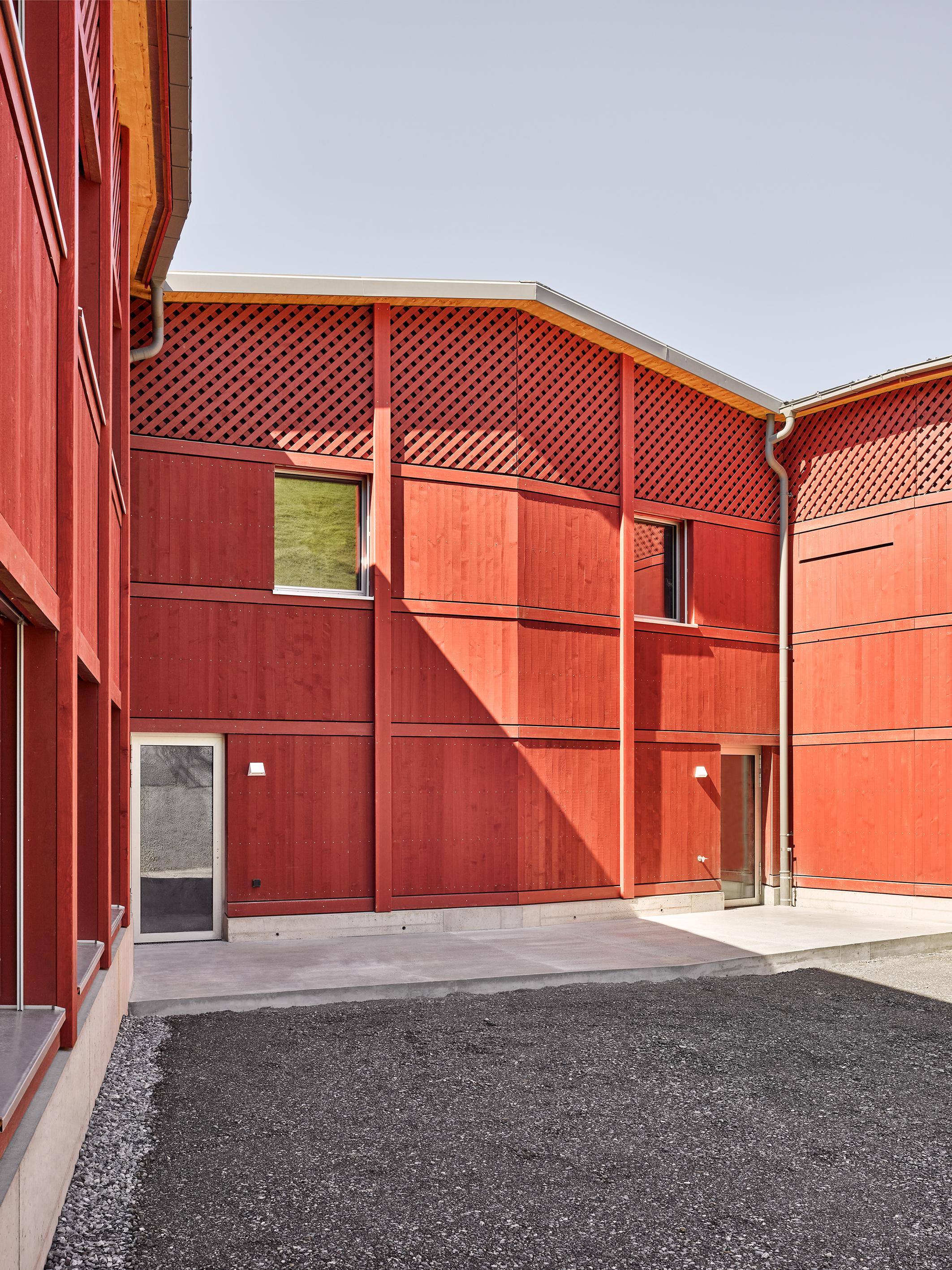 Rote Fassade mit Fenstern und Eingangstüren.