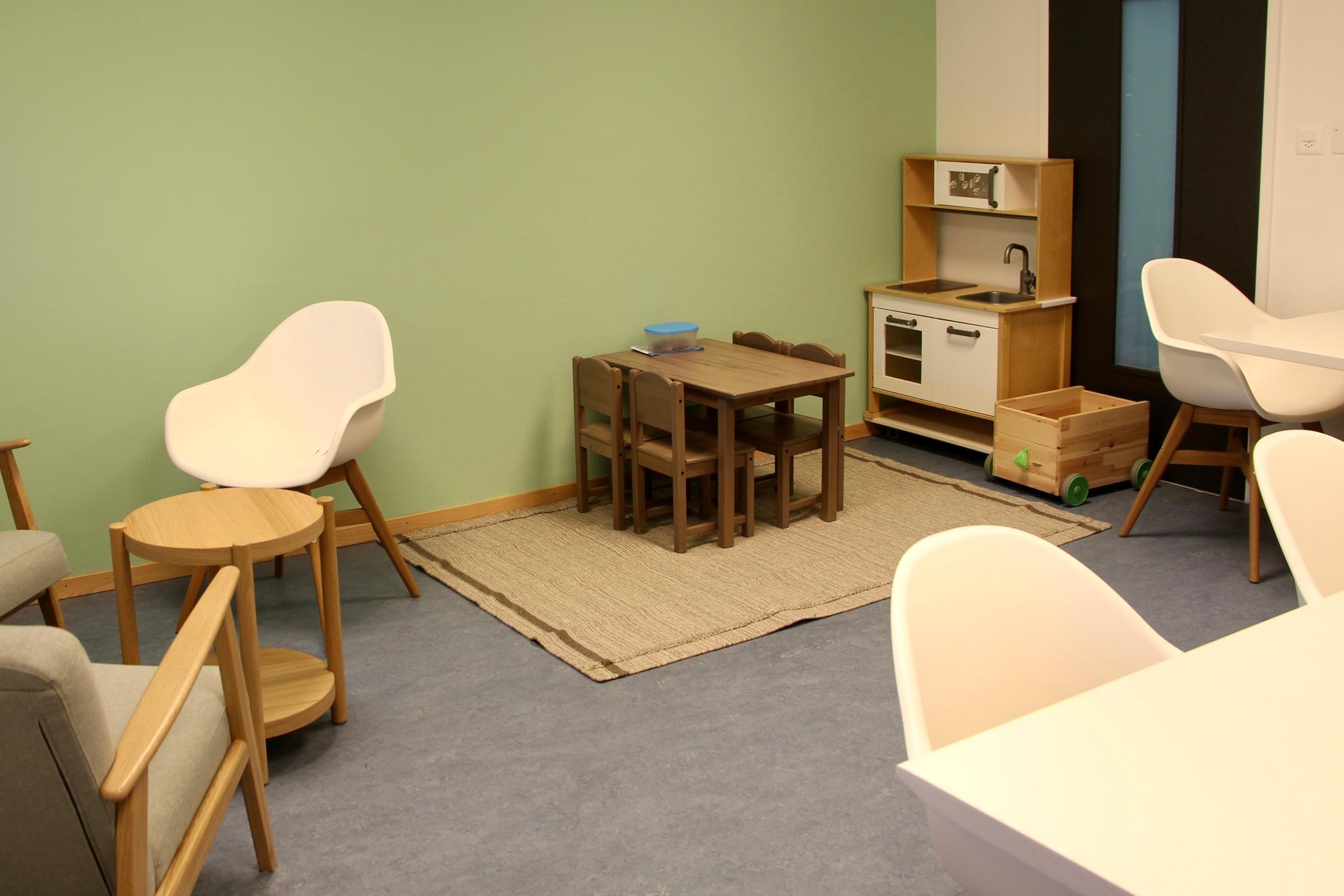 Raum mit Tischen und Stühlen und einer Kinderecke.