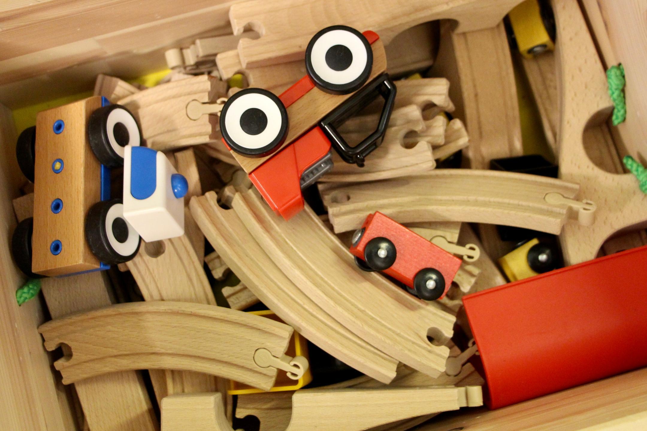 Spielkiste mit Schienen und Fahrzeugen aus Holz.