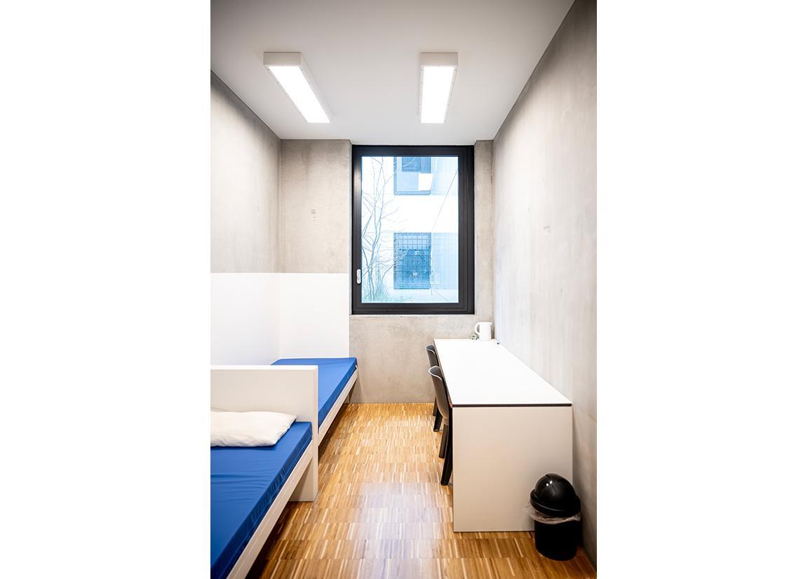 Eine Zelle in der vorläufigen Festnahme mit Fenster, zwei Betten und einem Tisch mit zwei Stühlen.