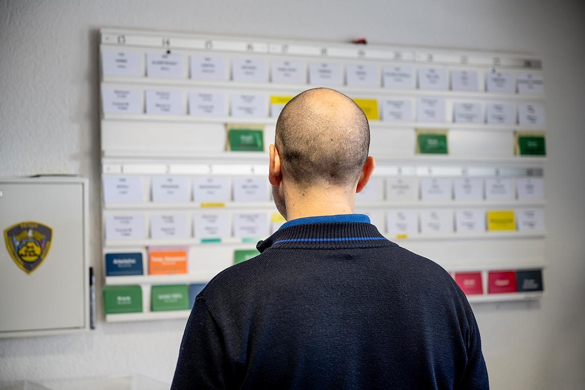 Mitarbeiter von hinten, er blick auf den Personalplan.