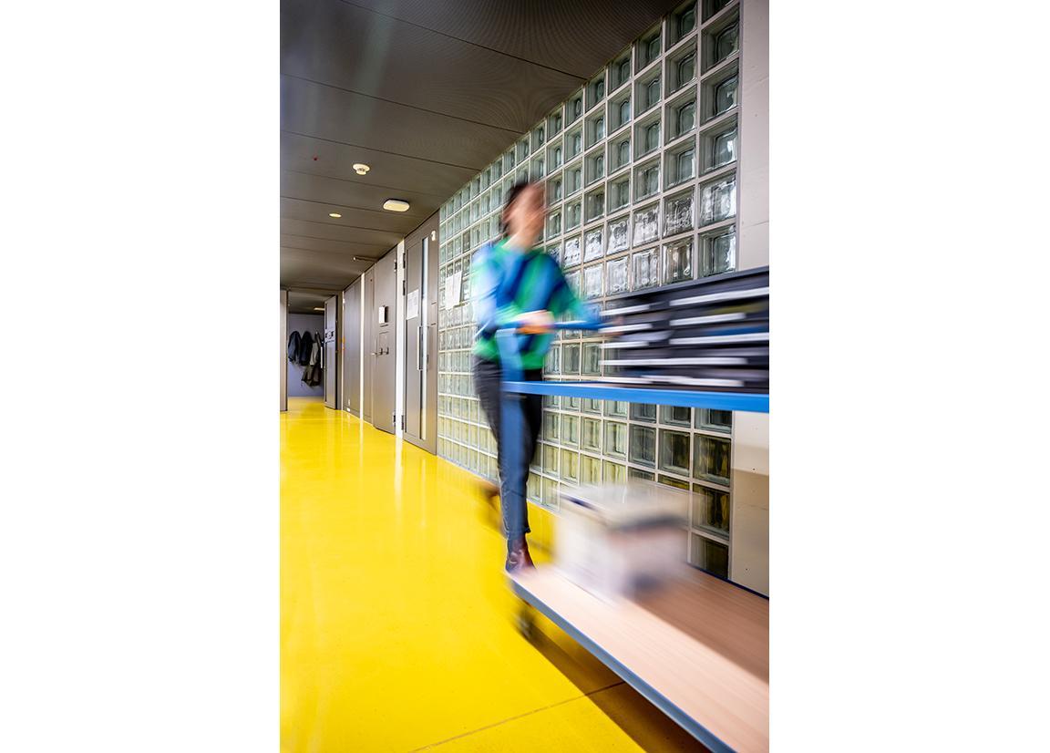 Auf einem Rollwagen werden die Fragebögen von einer Person an die Zellen verteilt.