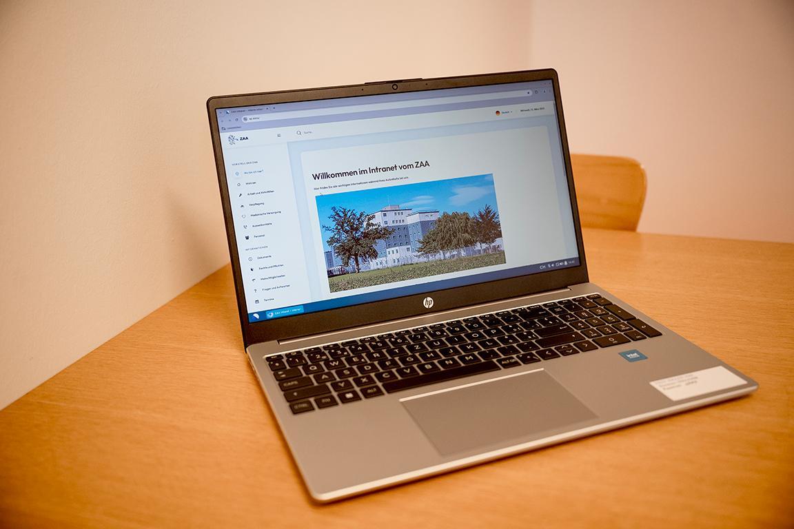 Auf einem leeren Tisch steht ein Laptop, auf dem Bildschirm zu sehen ist die Startseite des Gefängnis-Intranet.