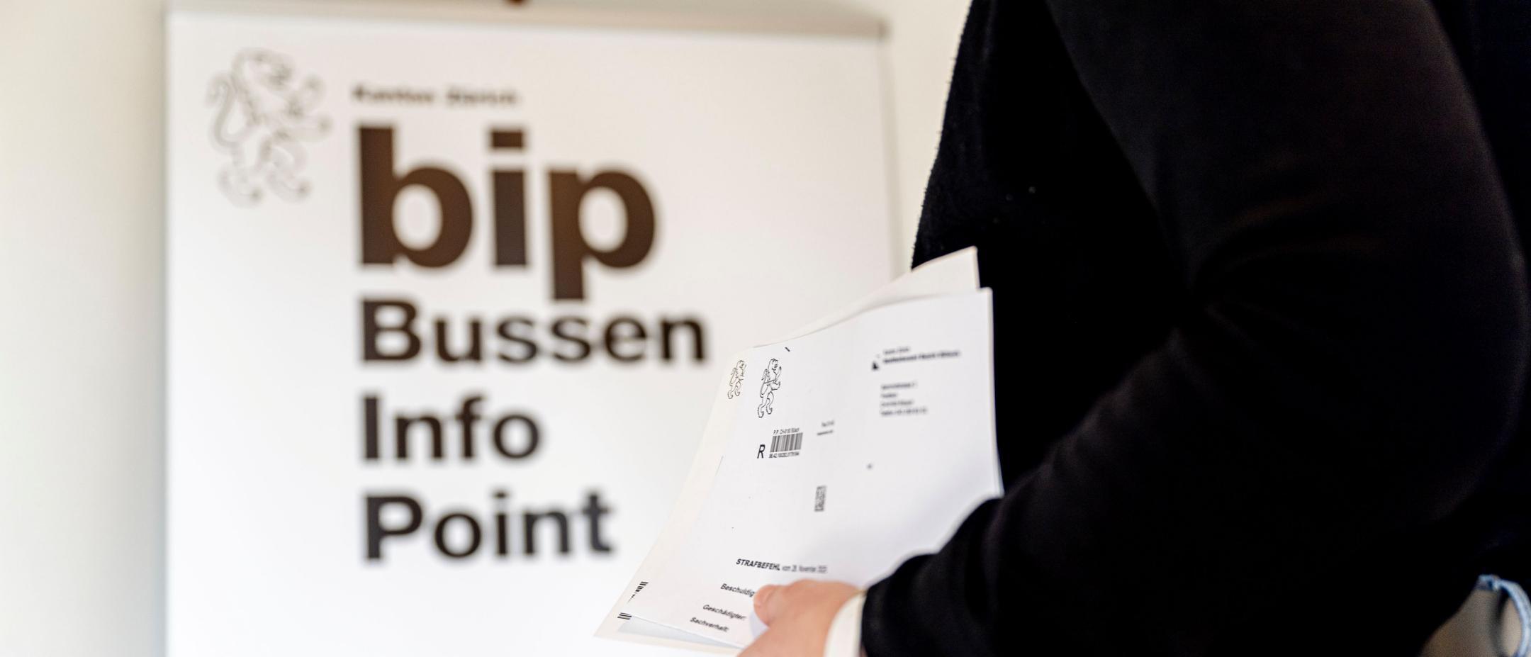 Person steht mit Zetteln für dem Bussen Info Point.
