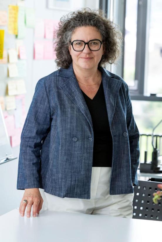 Amtsleiterin Mirjam Schlup steht vor einem Tisch, ihre Hand liegt auf dem Tisch und sie blickt geradeaus in die Kamera.