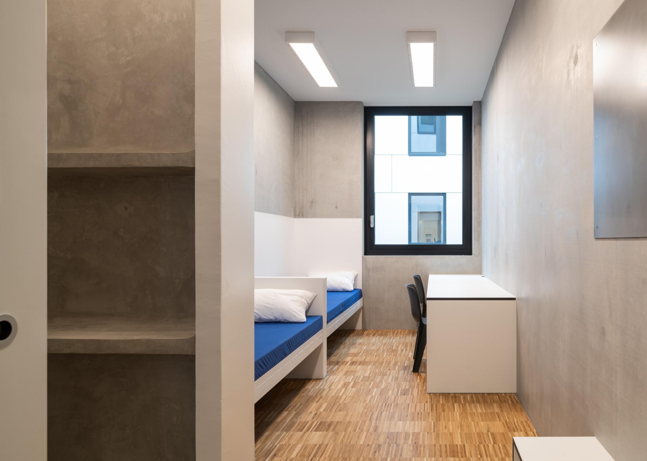 Ein Raum mit Fenster und zwei Schlafplätzen sowie einem Schreibtisch