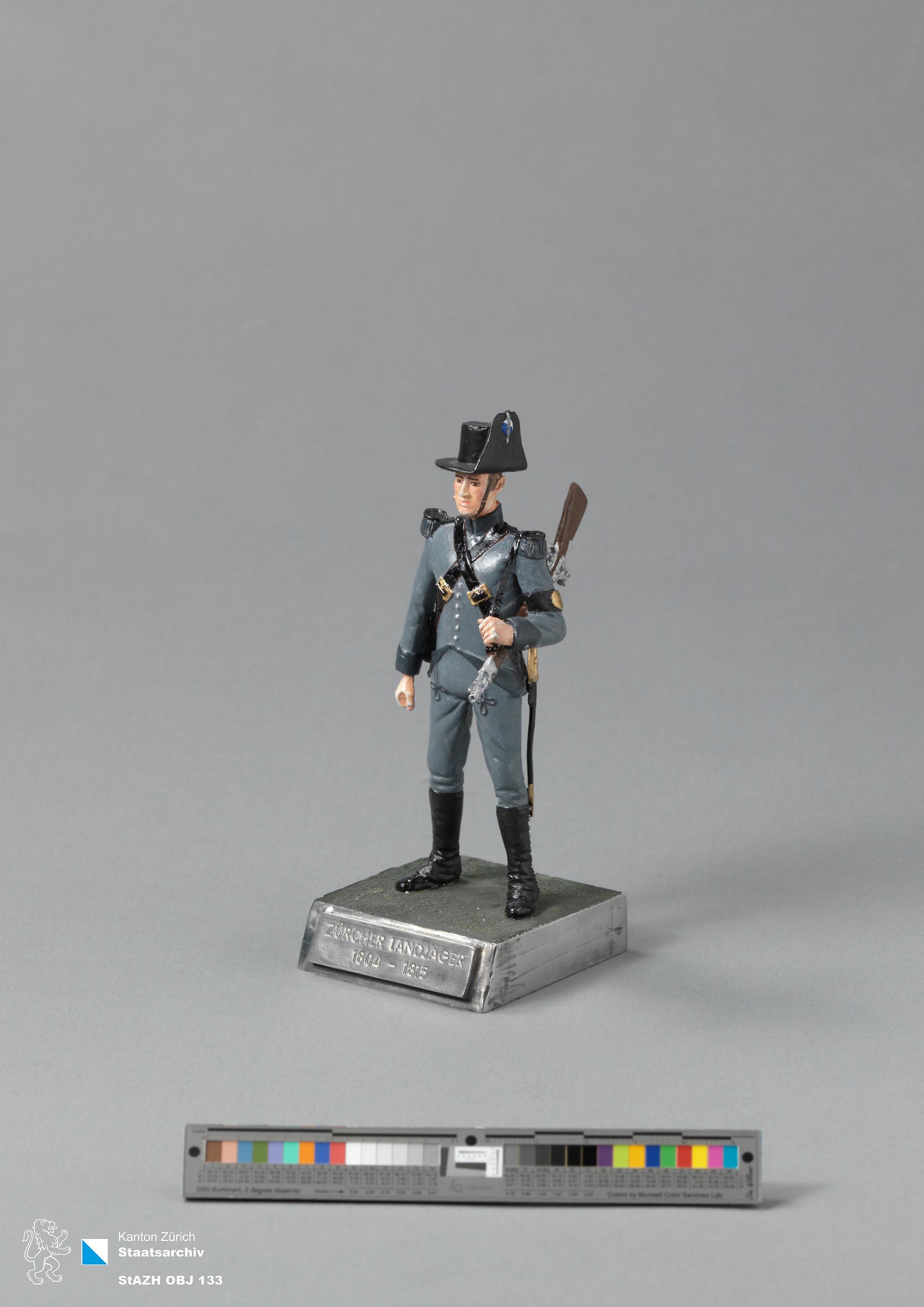 Hochrelief eines Zürcher Landjägers aus bemaltem Bleizinn. m Sockel eingraviert steht Zürcher Landjäger 1804-1815.