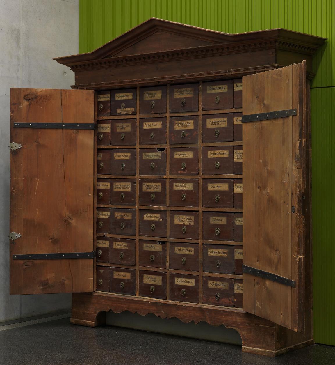 Holzschrank mit geöffneten Türen, Innenleben mit angeschriebenen Archivschubladen (Trucken)