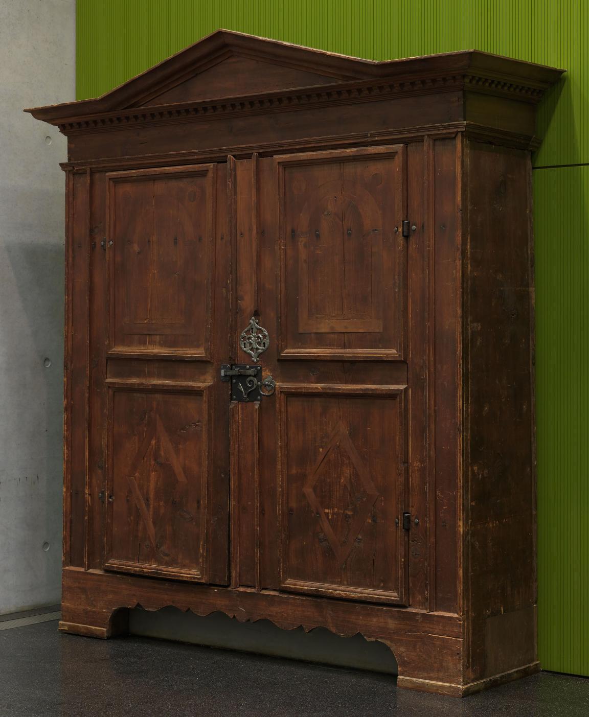 Hoher Holzschrank mit zwei Türen und kunstvollen Beschlägen