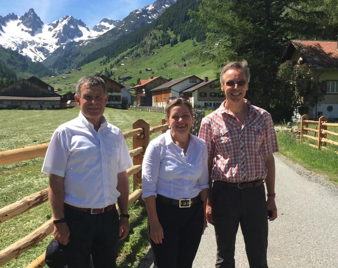 Regierungsrat Ernst Stocker mit zwei Personen vor Schneebergen.