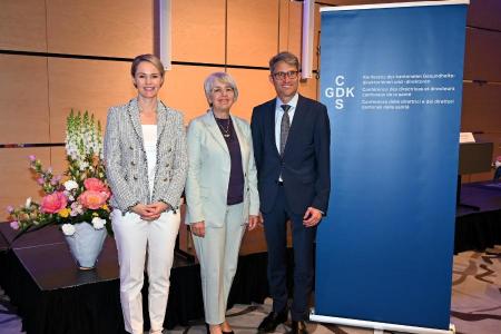 RR Rickli, BR Baume-Schneider und GDK-Präsident Engelberger posieren lächelnd vor einem blauen GDK-Banner bei der Jahrestagung.