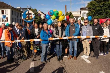 Eine Gruppe von Menschen mit Fahrrädern hält ein Absperrband vor dem Start des SlowUp in Uerikon.