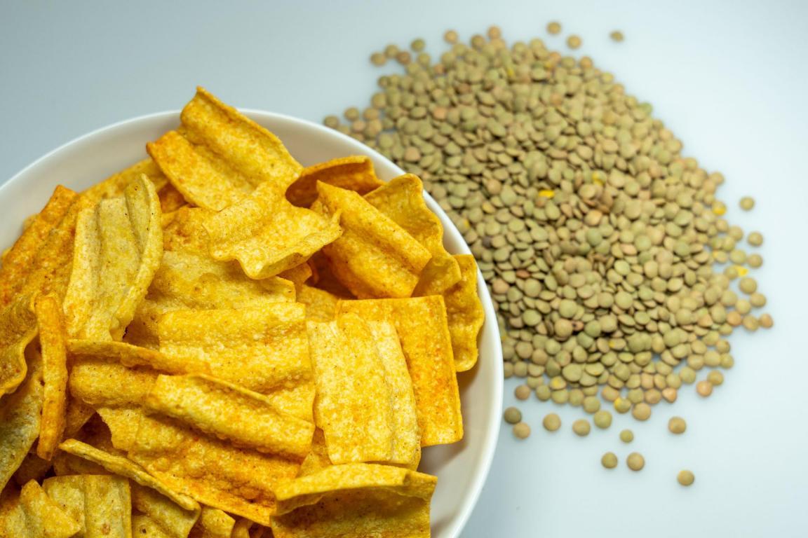 Chips in einer Schale und grüne Linsen nebendran liegend