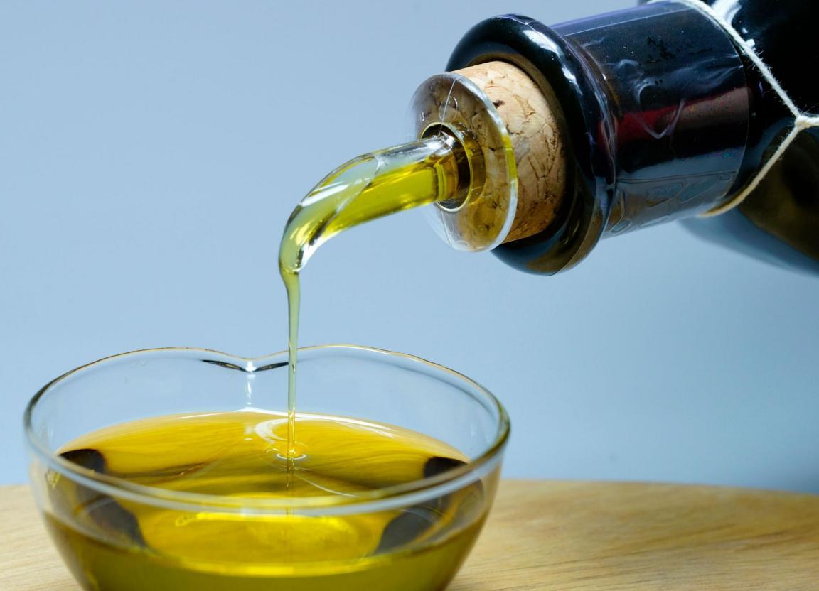 Aus einer Flasche wird Olivenöl in ein Gefäss abgefüllt.