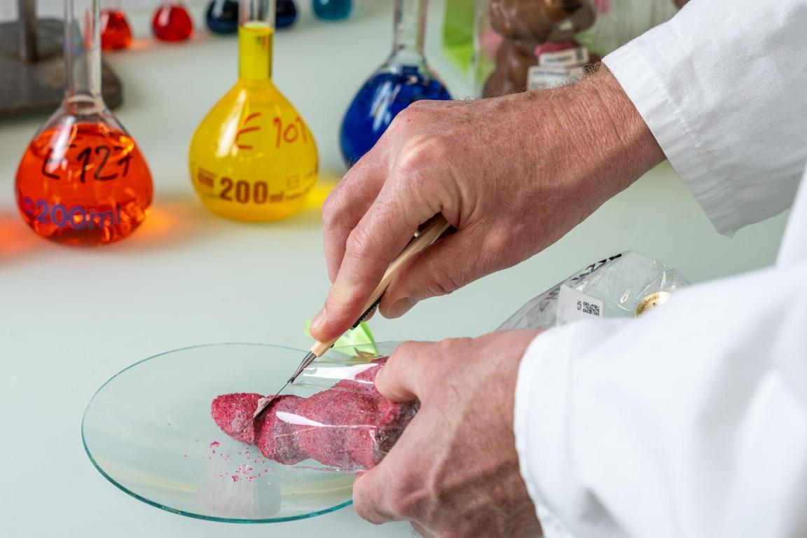 Ein Laborant untersucht einen Osterhasen im Labor auf Farbstoffe.