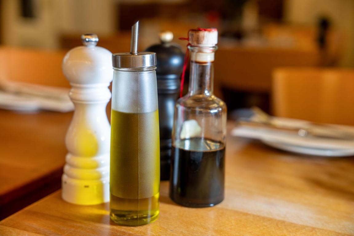 Das Foto zeigt eine Tischmenage in einem Restaurant mit Salz und Pfeffer, Essig und Öl.
