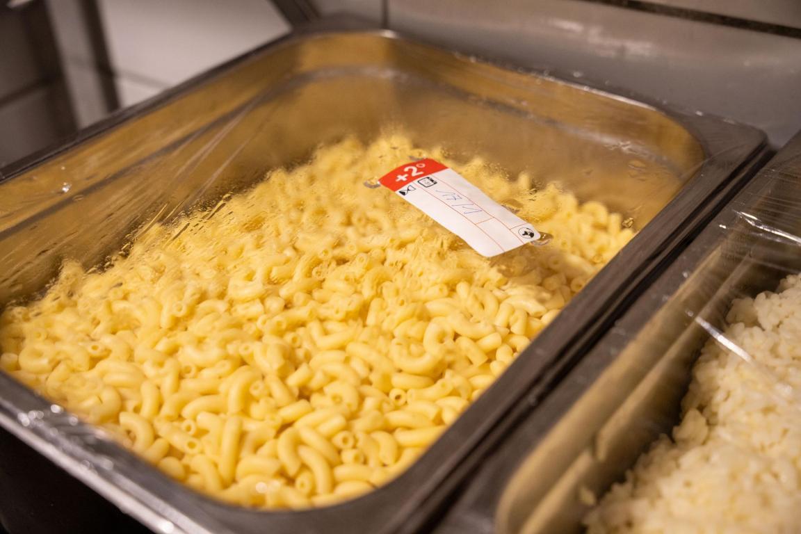 vorgekochte Hörnchennudeln und Reis in Edelstahlbehältern, abgedeckt mit Klarsichtfolie. 