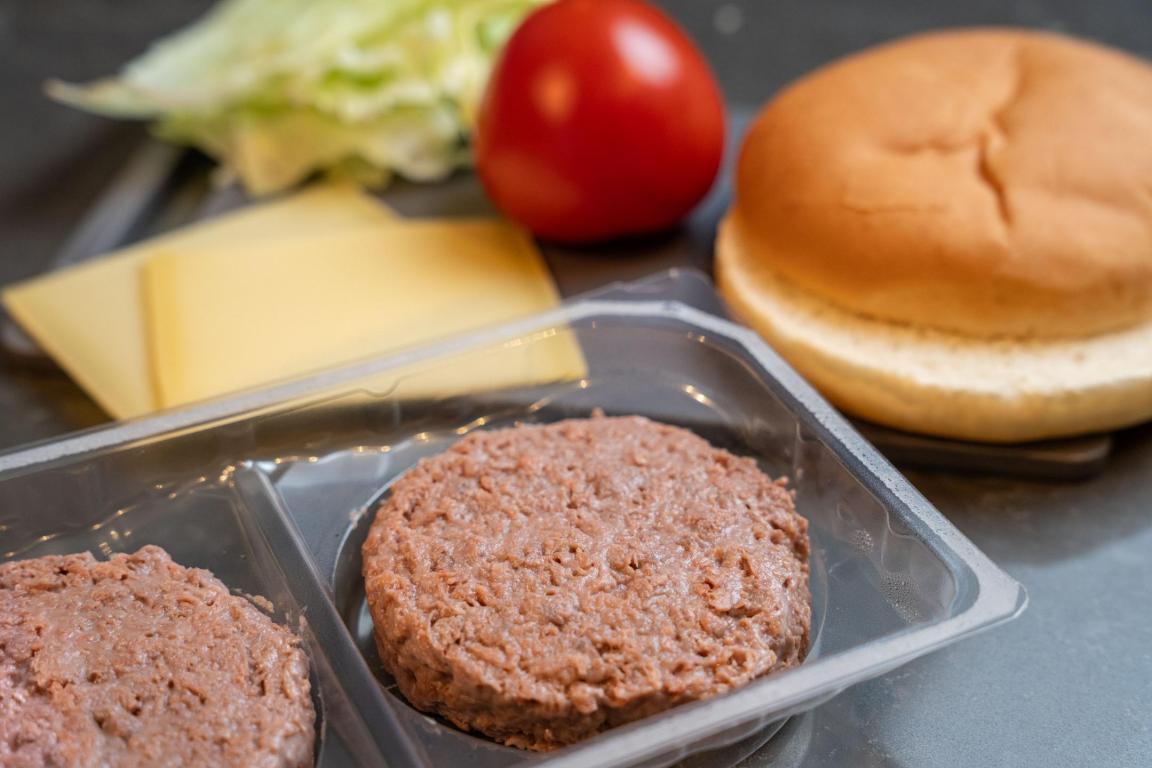 Veganer Burger mit weiteren klassischen Zutaten zur Zubereitung eines Cheeseburgers.