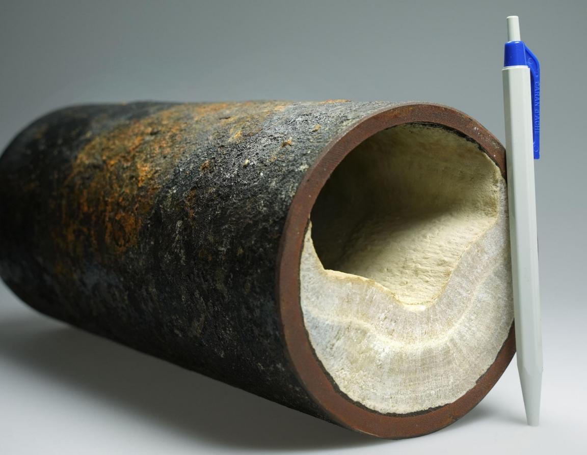 Metallrohr mit einer Kalkablagerung, die bis zur Hälfte reicht.