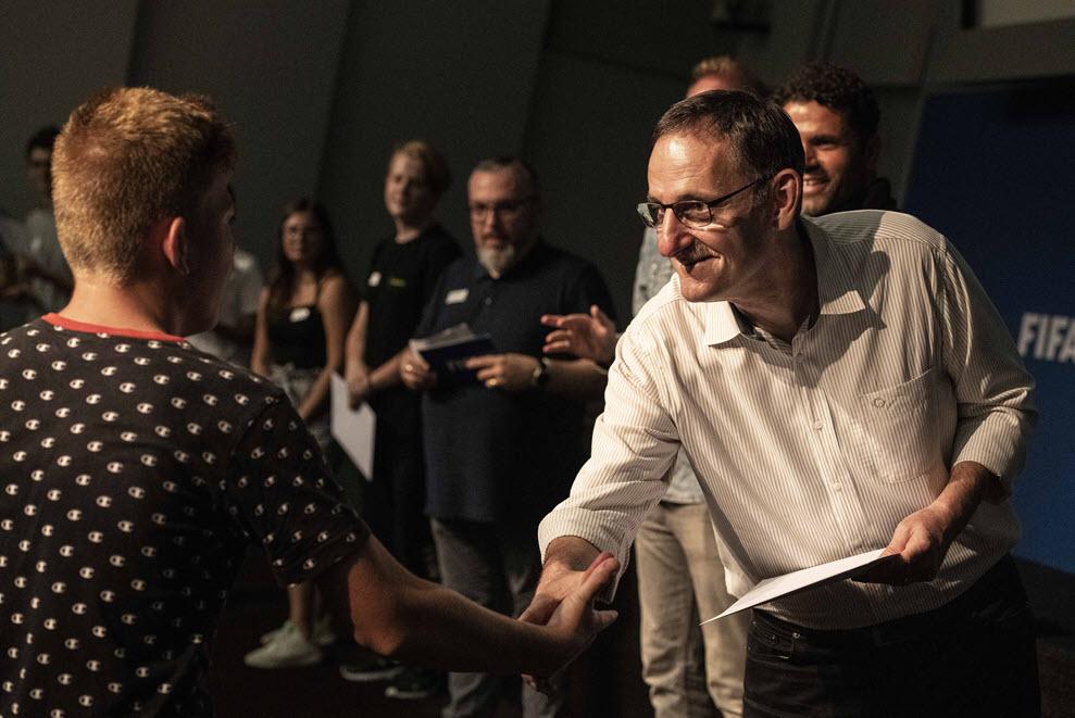 Regierungsrat Mario Fehr überreicht in der FIFA die Diplome an einen Jugendlichen, der die 1418coach-Ausbildung absolviert hat.