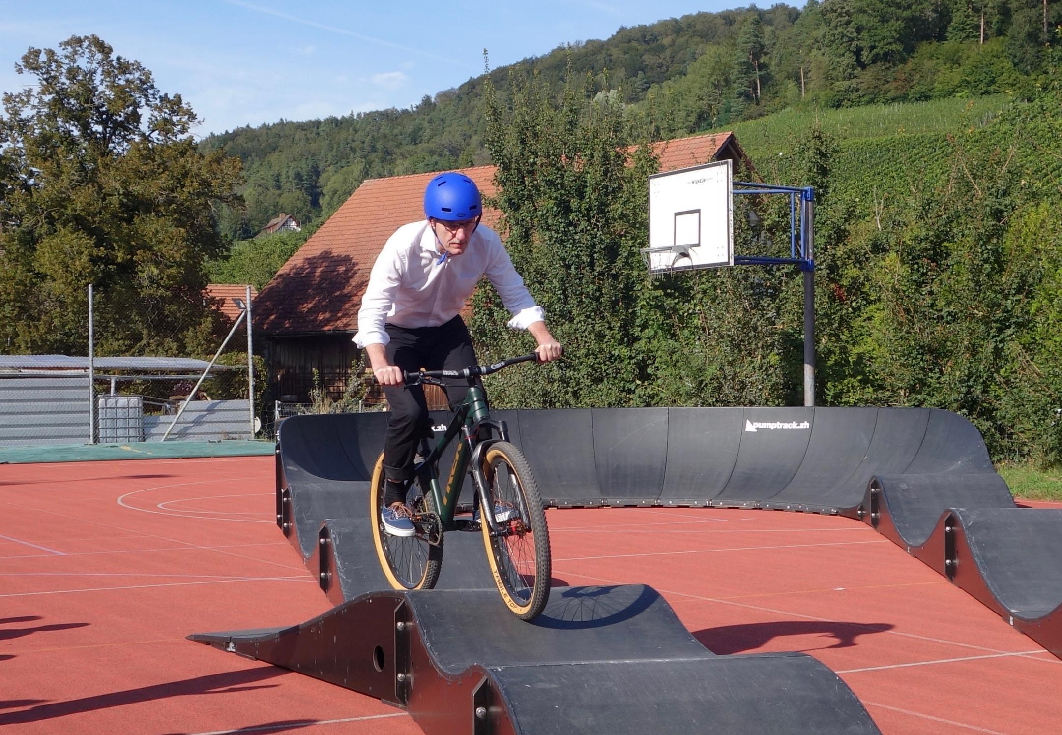 Regierungsrat Mario Fehr fährt auf dem roten Platz vom Sekundarschulhaus in Stammheim mit dem Velo eine Runde auf dem mobilen Pumptrack vom Sportamt des Kantons Zürich.