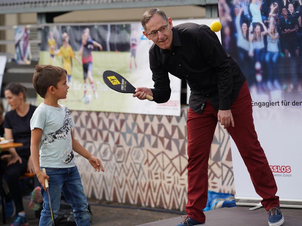 On the stage of Zurich’s sports festival, Government Councillor Mario Fehr and a boy demonstrate how the backhand game Street Racket is played.