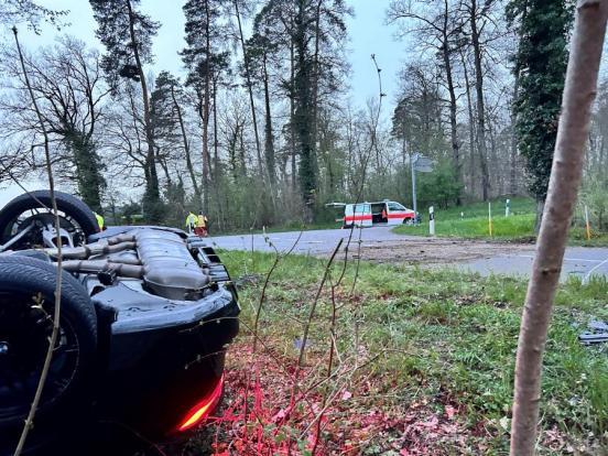 Unfallstelle. Grosses Spurenbild, vorne das Unfallfahrzeug auf dem Dach liegend, im Hintergrund ein Polizeiauto.