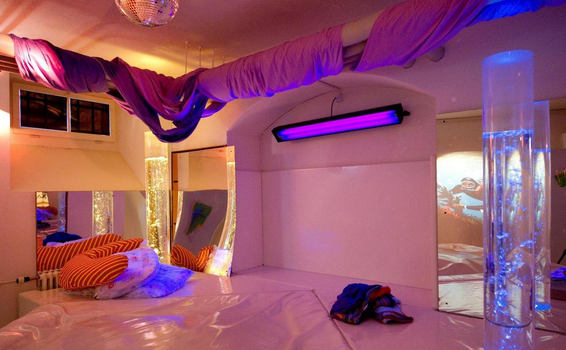 Der Freizeitraum (Snoezelraum) ist mit einem grossen, weissen Wasserbett, Kissen, Blubbersäulen und Licht- und Toneffekten ausgestattet.