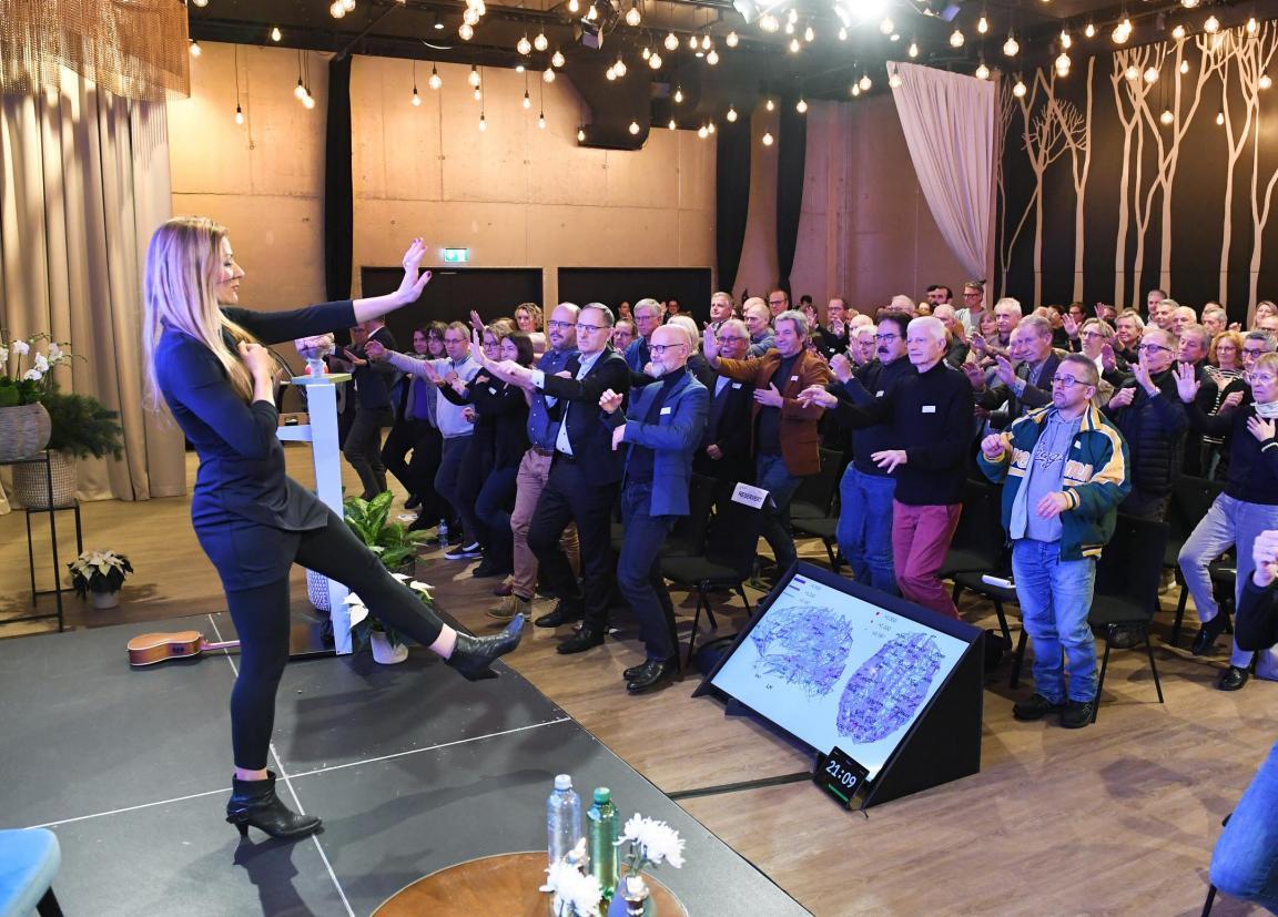 Barbara Studer zeigt am Forum eine Bewegungsübung auf der Bühne vor, das Publikum macht mit