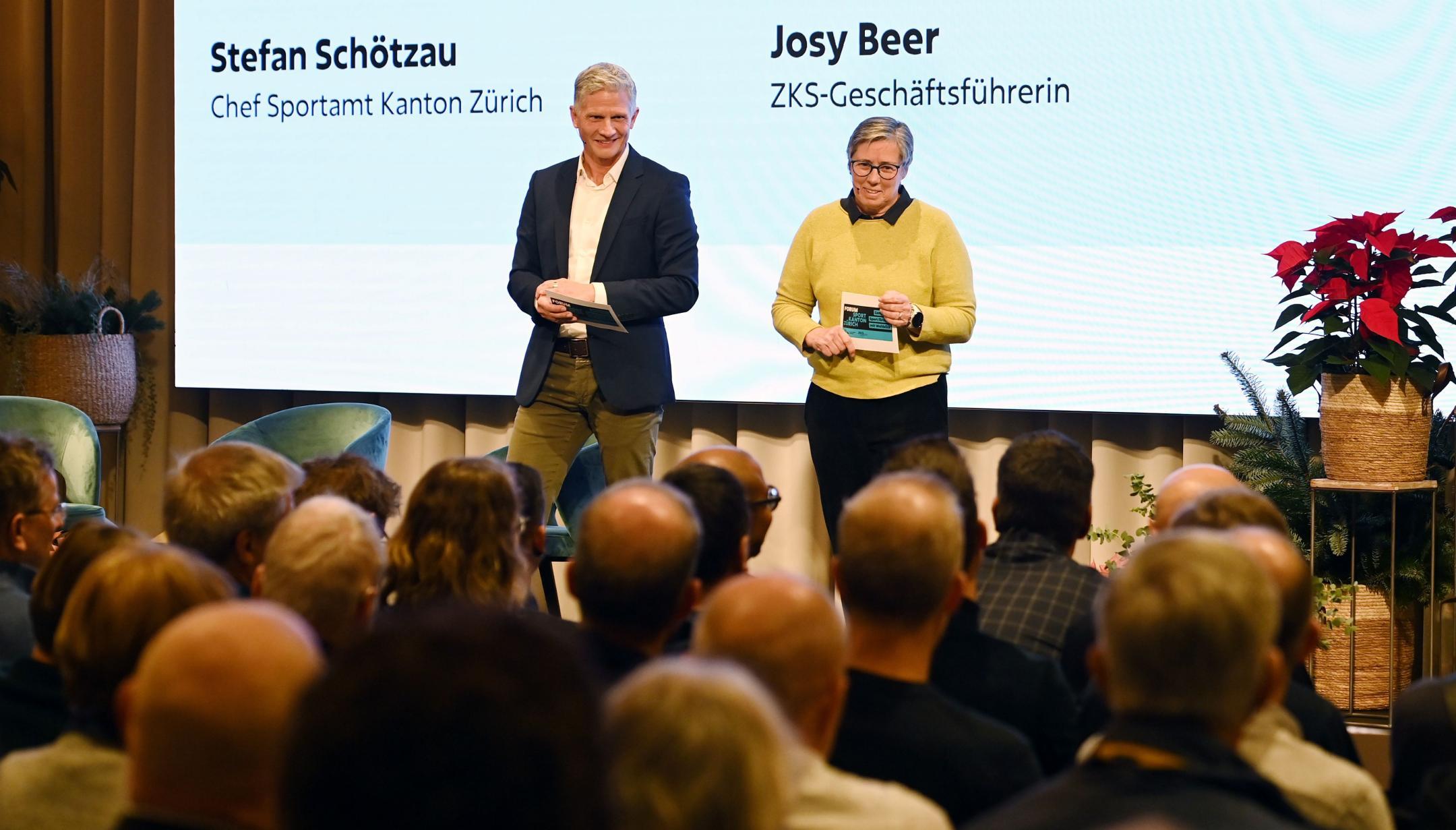 ein Mann und eine Frau stehen auf der Bühne und sprechen zum Publikum