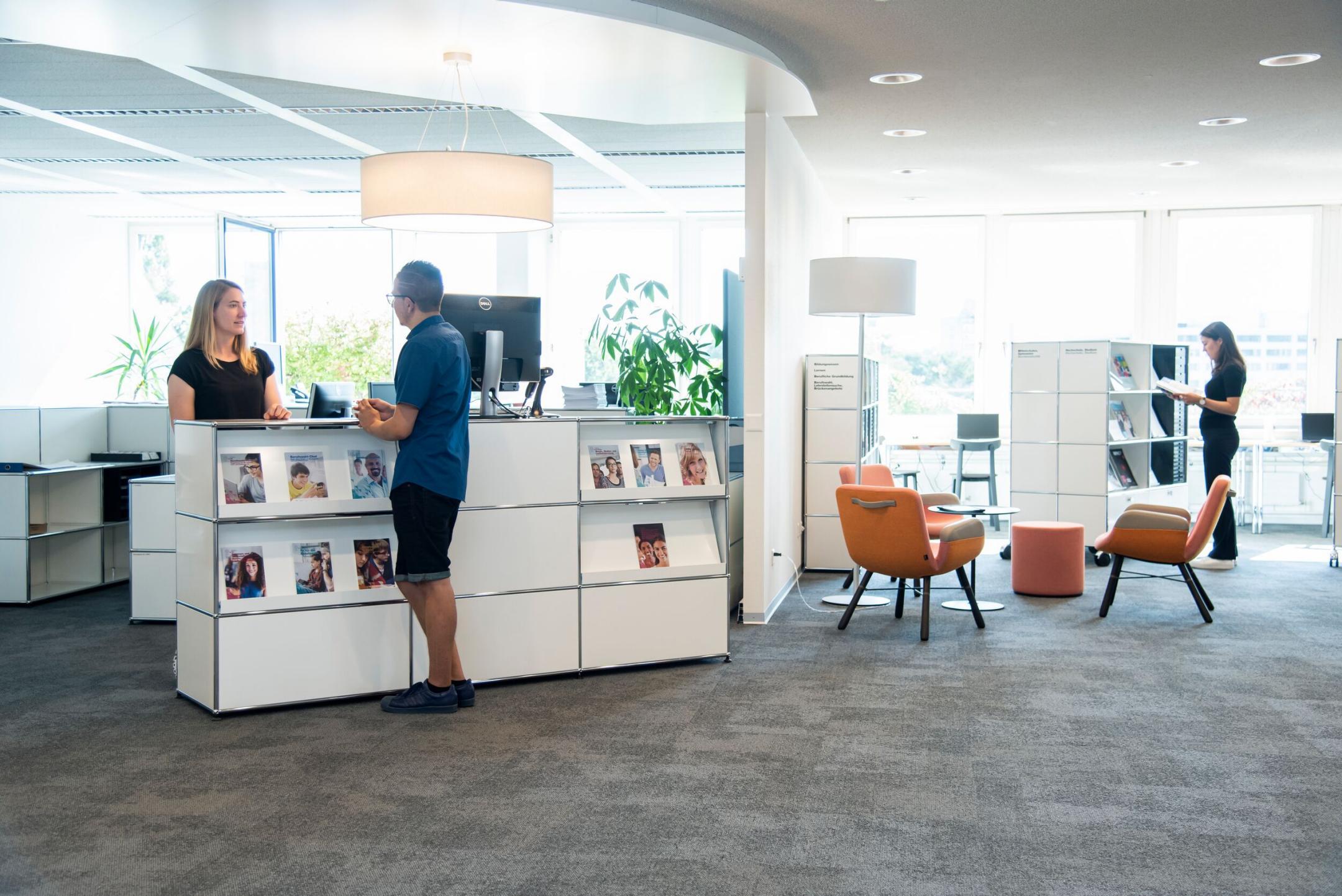 Ein Mann erkundigt sich an der Empfangstheke des biz bei einer Mitarbeiterin.