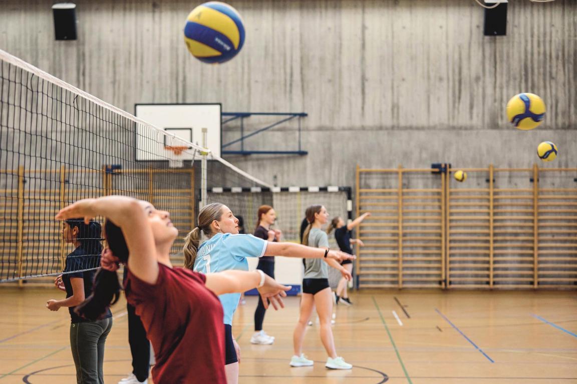Junge Frauen spielen Volleyball in einer Turnhalle