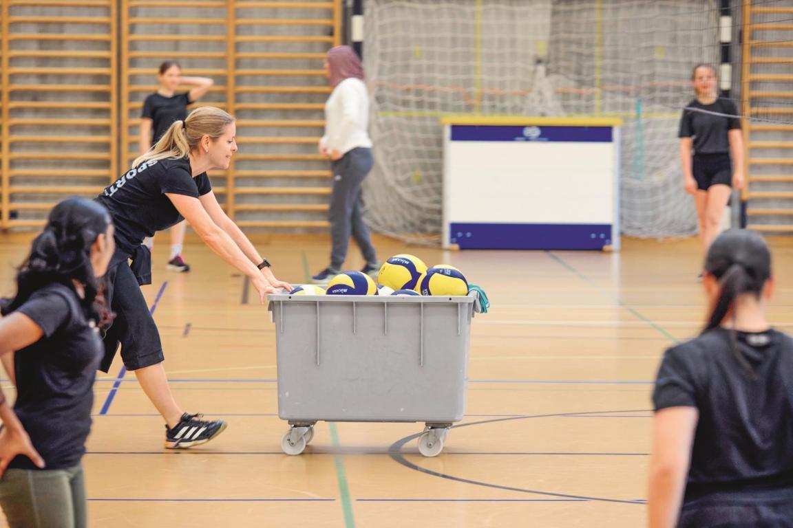 Schulklasse spielt Volleyball in Turnhalle